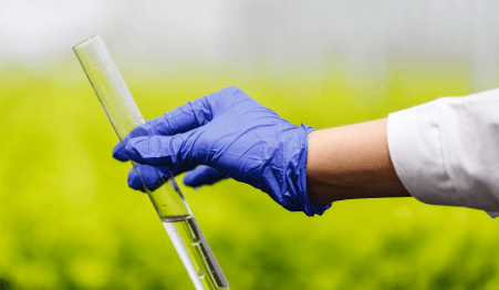 researcher holds test tube with water hand blue glove